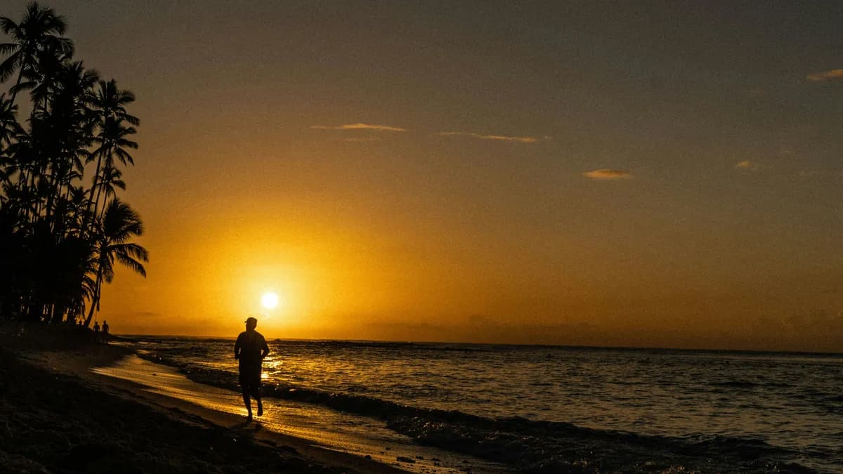 a person walking on a beach at sunset